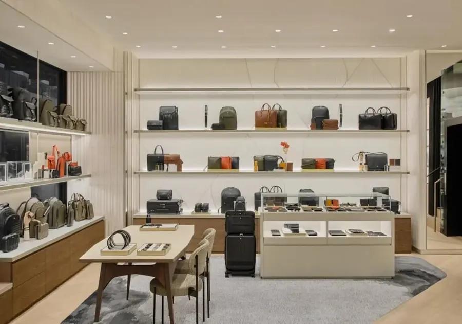 Wall of Montblanc leather goods with bags and small leather pieces on light shelves, a wooden table in front